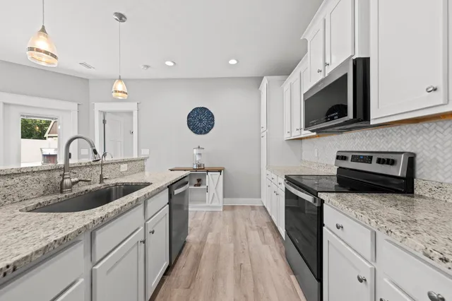a kitchen with a sink dishwasher stove and microwave with wooden floor