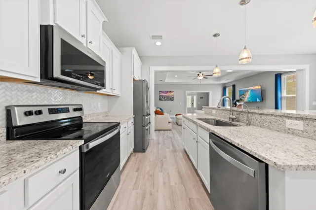 a kitchen with stainless steel appliances granite countertop a stove a sink and a microwave