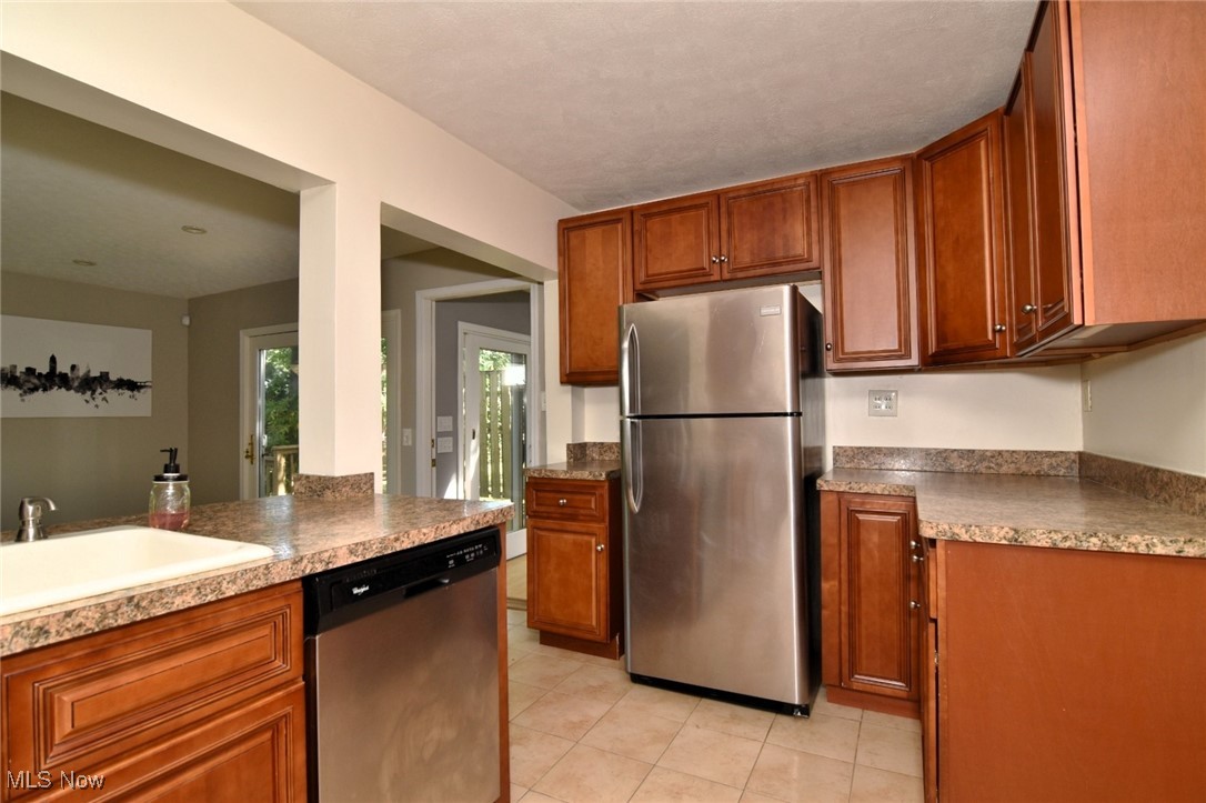 3679 Fenley Road Cleveland Heights, OH 44121 - Photo 15 of 45 Kitchen with appliances with stainless steel finishes, brown cabinetry, and light tile patterned flooring