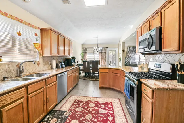 a large kitchen with stainless steel appliances granite countertop a stove a sink dishwasher a oven with wooden cabinets and floor