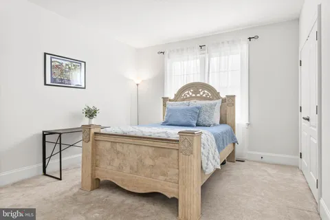 a bedroom with a bed a chair and a large window