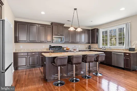 a kitchen with kitchen island granite countertop wooden floors and wooden cabinets