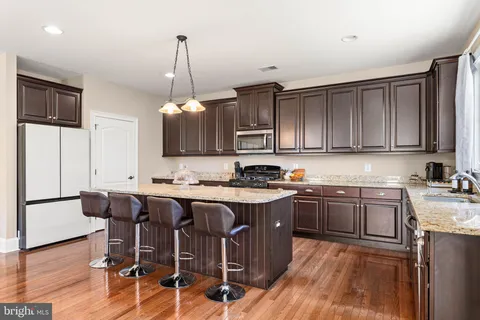 a kitchen with stainless steel appliances granite countertop a stove top oven a refrigerator a sink and dishwasher with wooden floor