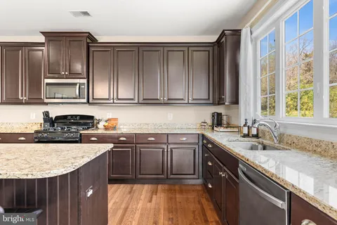 a kitchen with stainless steel appliances granite countertop a sink stove and cabinets