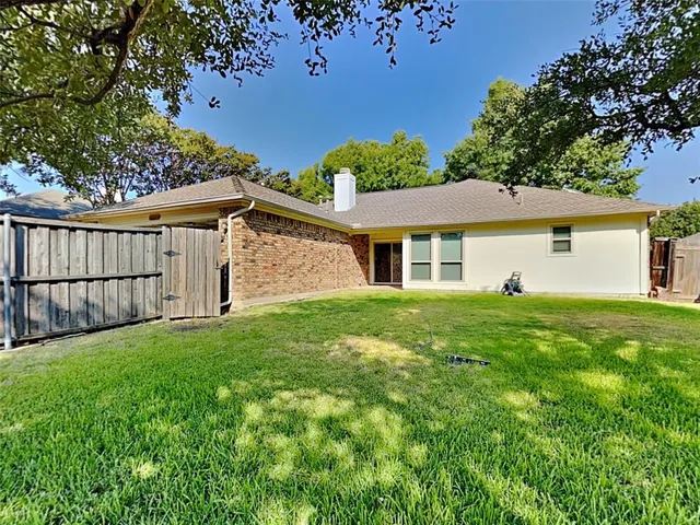 a view of a yard in front of a house with plants and large tree