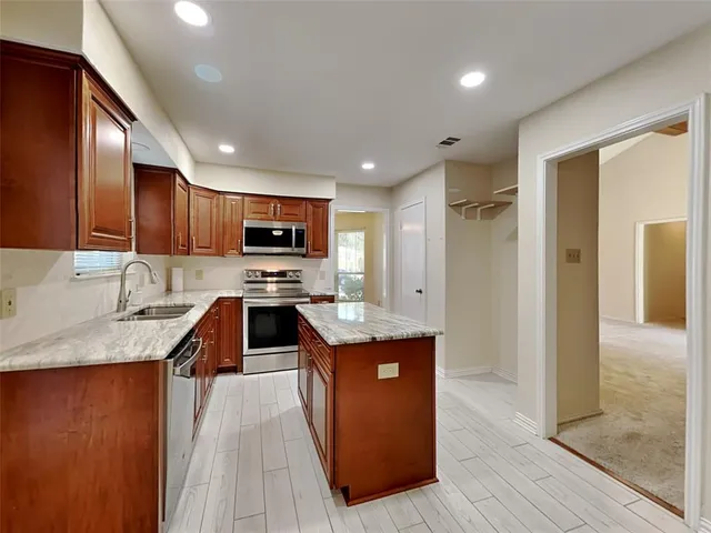a kitchen with stainless steel appliances granite countertop a stove top oven a sink and a refrigerator