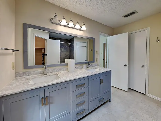 a bathroom with a granite countertop double vanity sink and a mirror