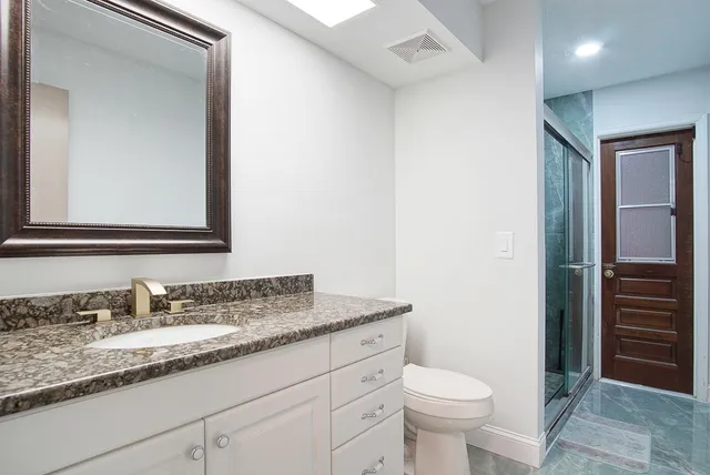 a bathroom with a granite countertop toilet sink and mirror