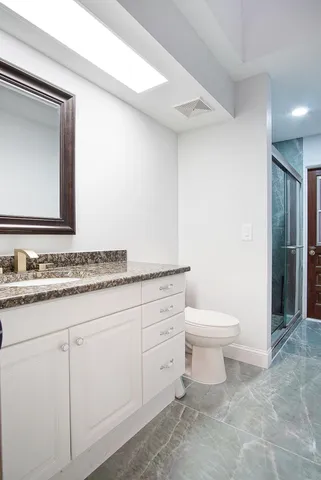 a bathroom with a granite countertop toilet sink and mirror