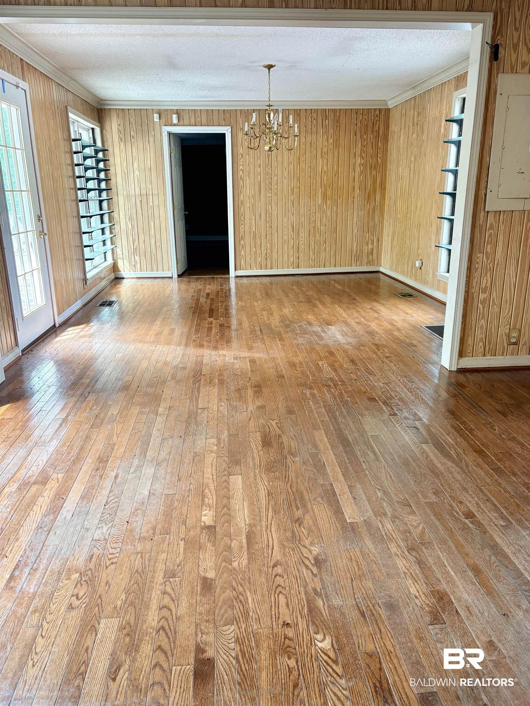 1018 Bates Road Evergreen, AL 36401 - Photo 13 of 21 Unfurnished room featuring hardwood / wood-style flooring, ornamental molding, suspended lighting, electric panel, and wooden walls