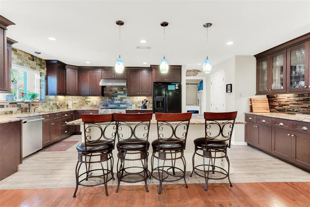 319 East Spring Valley Road Richardson, TX 75081 - Photo 5 of 22 Kitchen featuring wood cabinetry, an island with seating, pendant lighting, and a tile backsplash