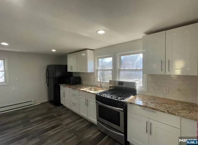 a kitchen with granite countertop stainless steel appliances a stove sink and cabinets