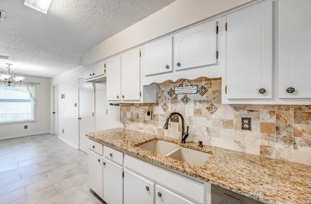 a kitchen with granite countertop white cabinets and sink