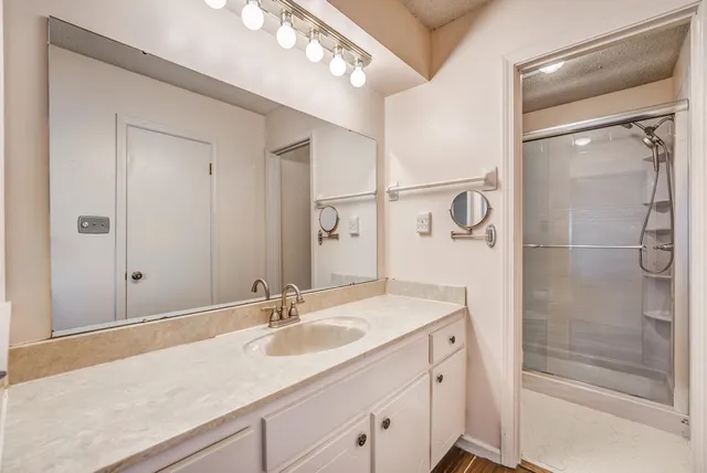 a bathroom with a shower sink vanity granite and mirror