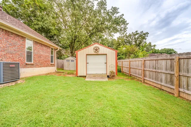 a large tree in front of a house with wooden fence