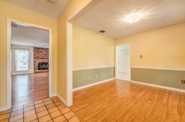a view of a hallway with wooden floor and a bathroom