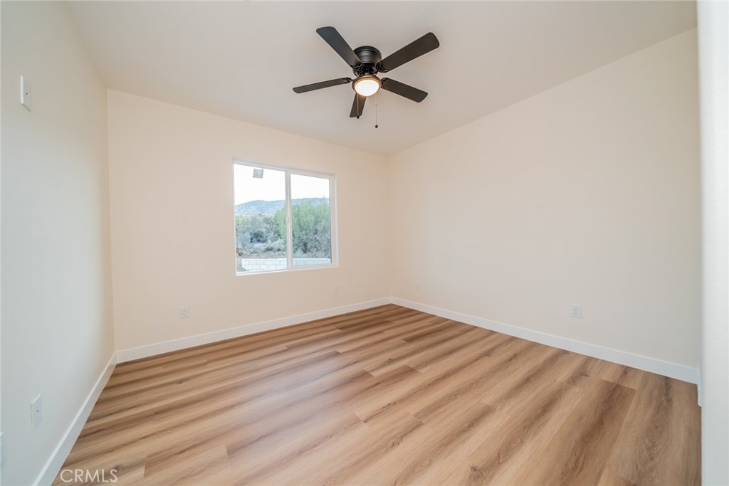 1114 Hollister Road Pinon Hills, CA 92372 - Photo 23 of 61 an empty room with wooden floor and ceiling fan