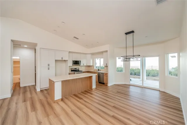 a large kitchen with cabinets wooden floor and stainless steel appliances