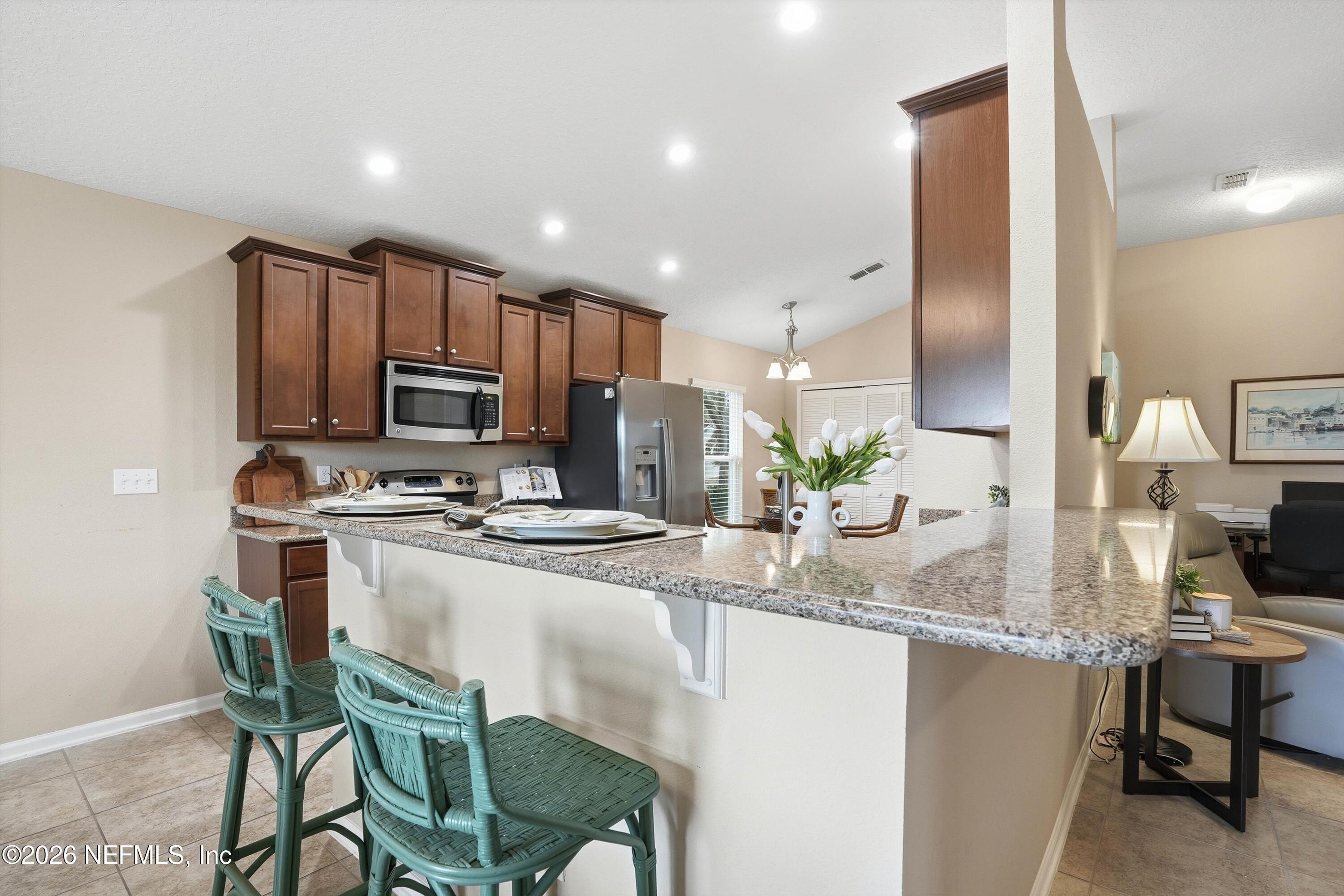 1833 Indigo Street Fernandina Beach, FL 32034 - Photo 10 of 41 a kitchen with kitchen island granite countertop a table chairs microwave and refrigerator