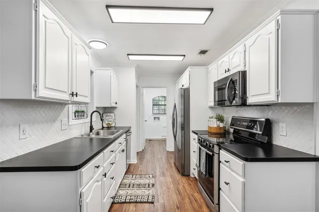 a kitchen with stainless steel appliances a sink a stove a microwave a sink a refrigerator and cabinets