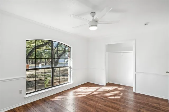 a view of an empty room with a window and wooden floor