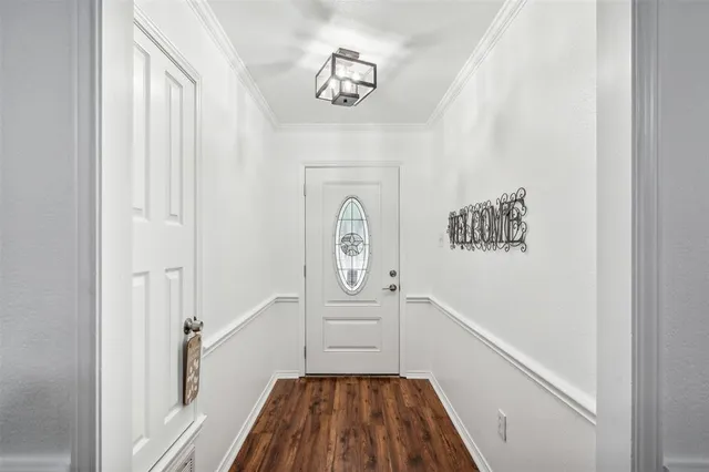 a hallway with wooden floor a chandelier and entryway