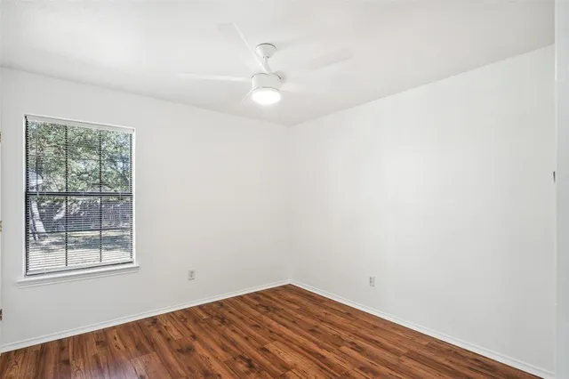 an empty room with a window and a fan