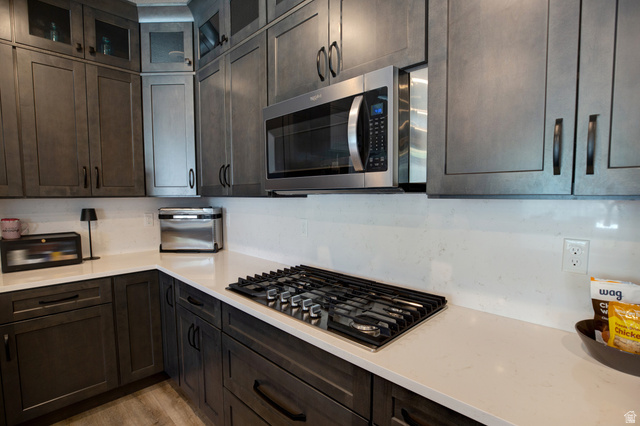 983 South 950 West Provo, UT 84601 - Photo 13 of 56 Modern kitchen featuring dark wood-finish cabinetry, light-toned countertops, a built-in gas cooktop, and a stainless steel microwave