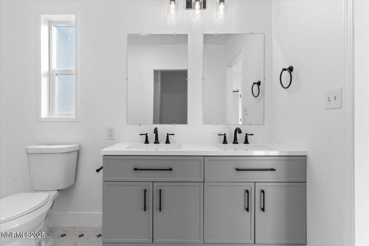 11305 Fir Drive Reno, NV 89506 - Photo 17 of 35 a bathroom with a toilet a sink a mirror and a window