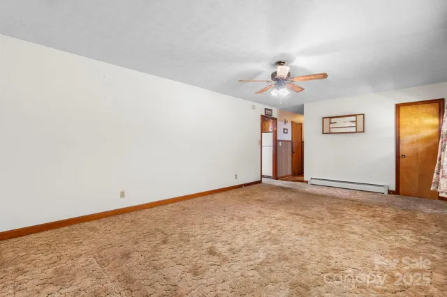 an empty room with chandelier fan and windows