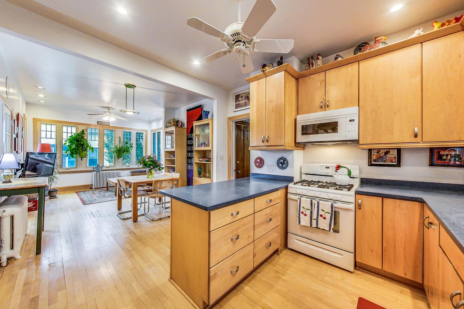 7221 North Ridge Boulevard Chicago, IL 60645 - Photo 13 of 48 a kitchen with stainless steel appliances granite countertop a stove top oven a sink dishwasher and white cabinets with wooden floor