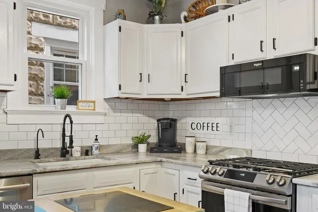 a kitchen with stainless steel appliances granite countertop white cabinets and a stove a oven with white countertops
