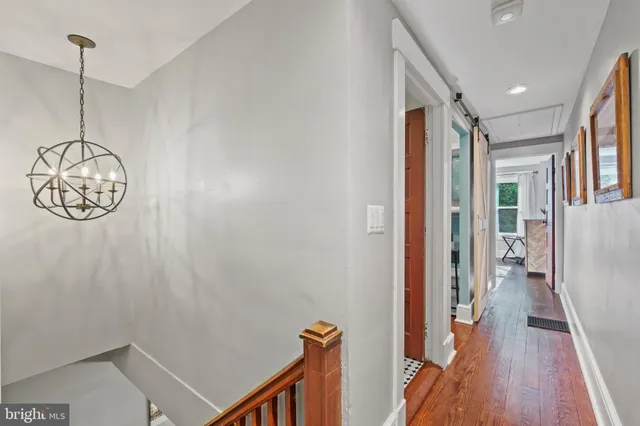 a view of a hallway with wooden floor and a chandelier