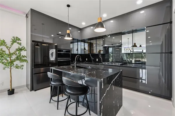a kitchen with stainless steel appliances kitchen island granite countertop a table chairs and a refrigerator
