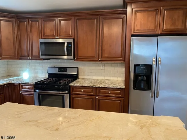 a kitchen with stainless steel appliances granite countertop a stove top oven a refrigerator and dishwasher