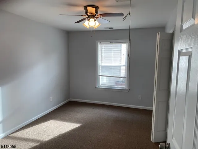 an empty room with windows and fan