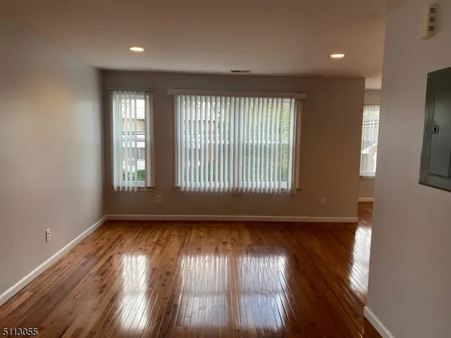 a view of an empty room and wooden floor and a window