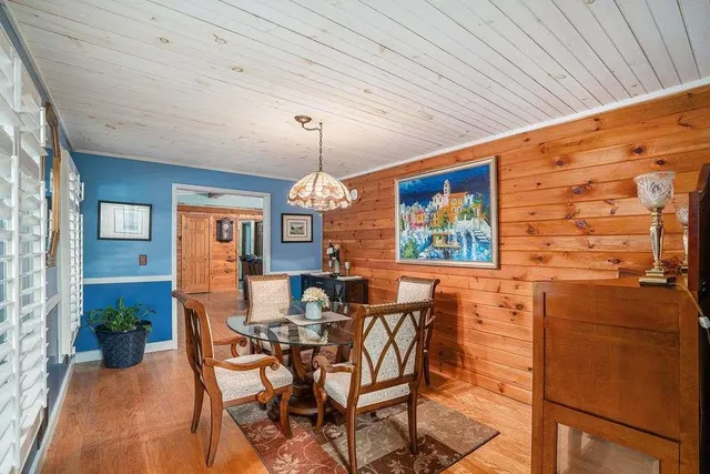a view of a dining room with furniture one side kitchen view and wooden floor