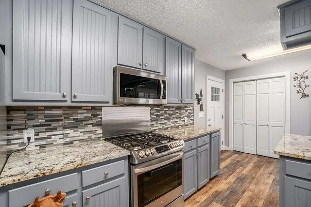 a kitchen with granite countertop cabinets stainless steel appliances and wooden floor