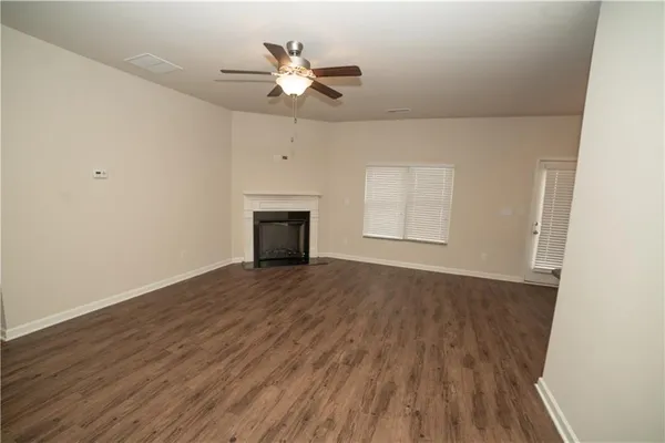 an empty room with wooden floor fan and windows