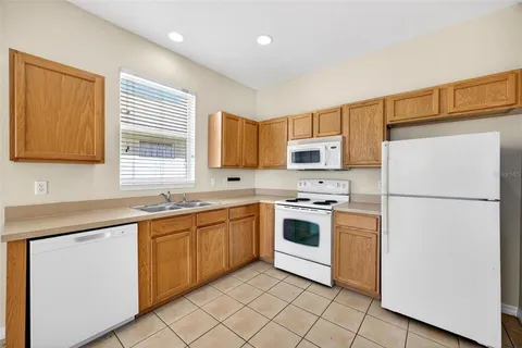 a kitchen with stainless steel appliances granite countertop white cabinets a sink a stove a refrigerator and a microwave