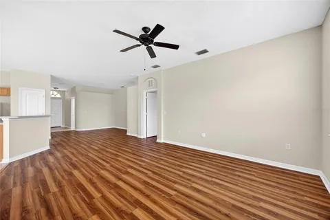 a view of empty room with wooden floor and ceiling fan