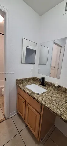 a bathroom with a granite countertop toilet and a sink
