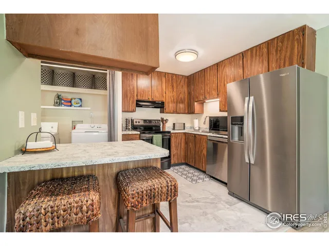 a kitchen with granite countertop a refrigerator a sink a stove and wooden cabinets