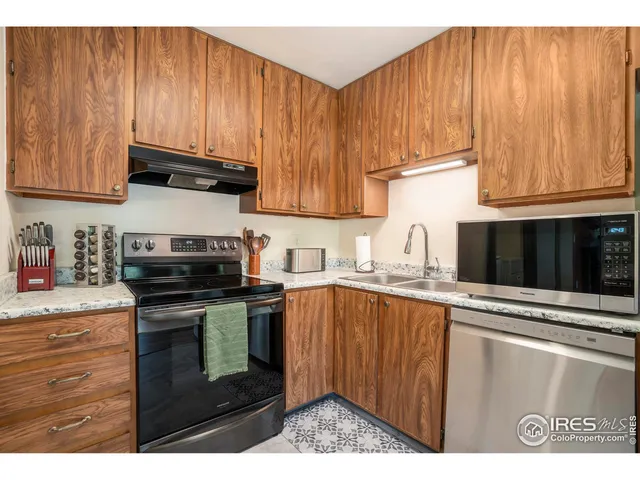 a kitchen with stainless steel appliances granite countertop a stove a sink dishwasher and a refrigerator with wooden cabinets