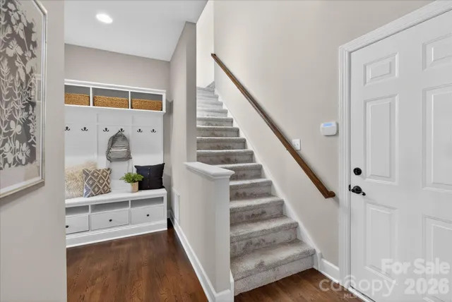 a view of a hallway to a livingroom with wooden floor and stairs