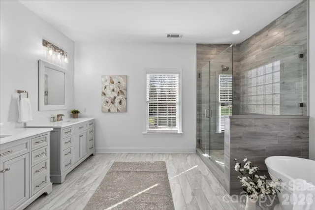 a bathroom with a double vanity sink a toilet a mirror and shower