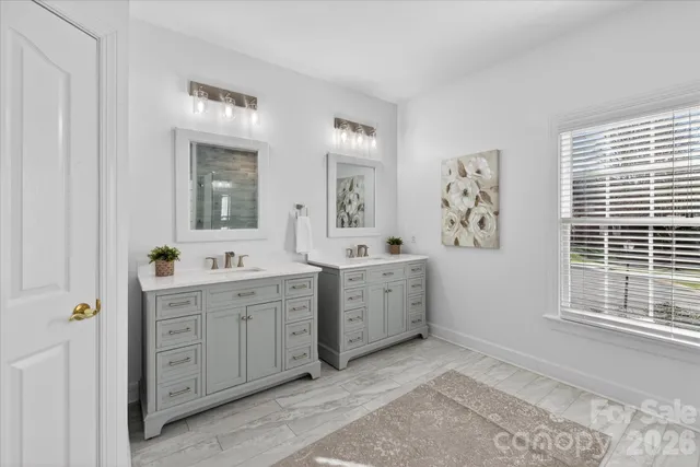 a spacious bathroom with a double vanity sink a mirror a window and a bathtub