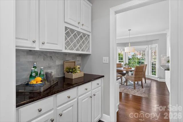 a kitchen with white cabinets and wooden floor