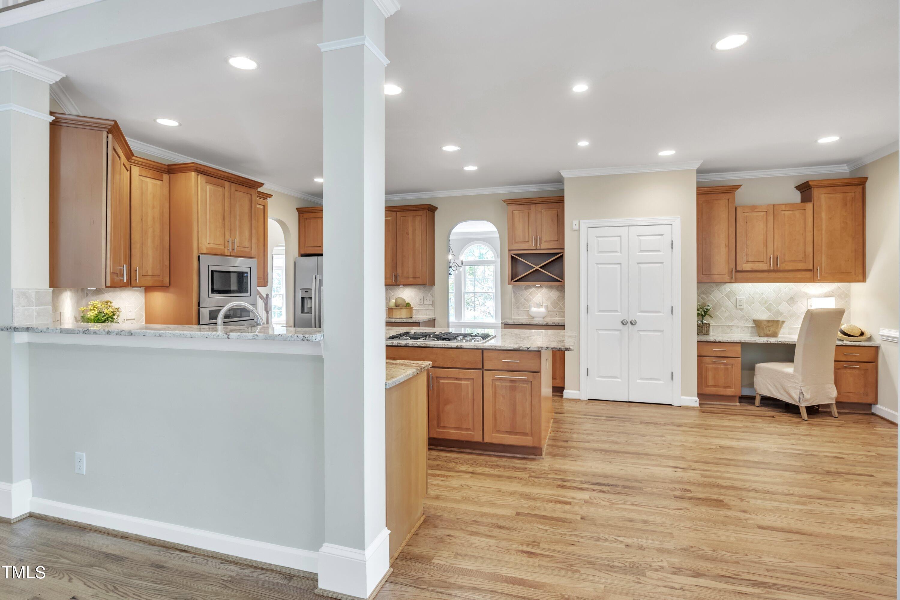 12208 Jasmine Cove Way Raleigh, NC 27614 - Photo 15 of 57 a open kitchen with kitchen island a sink dishwasher stove and white cabinets with wooden floor